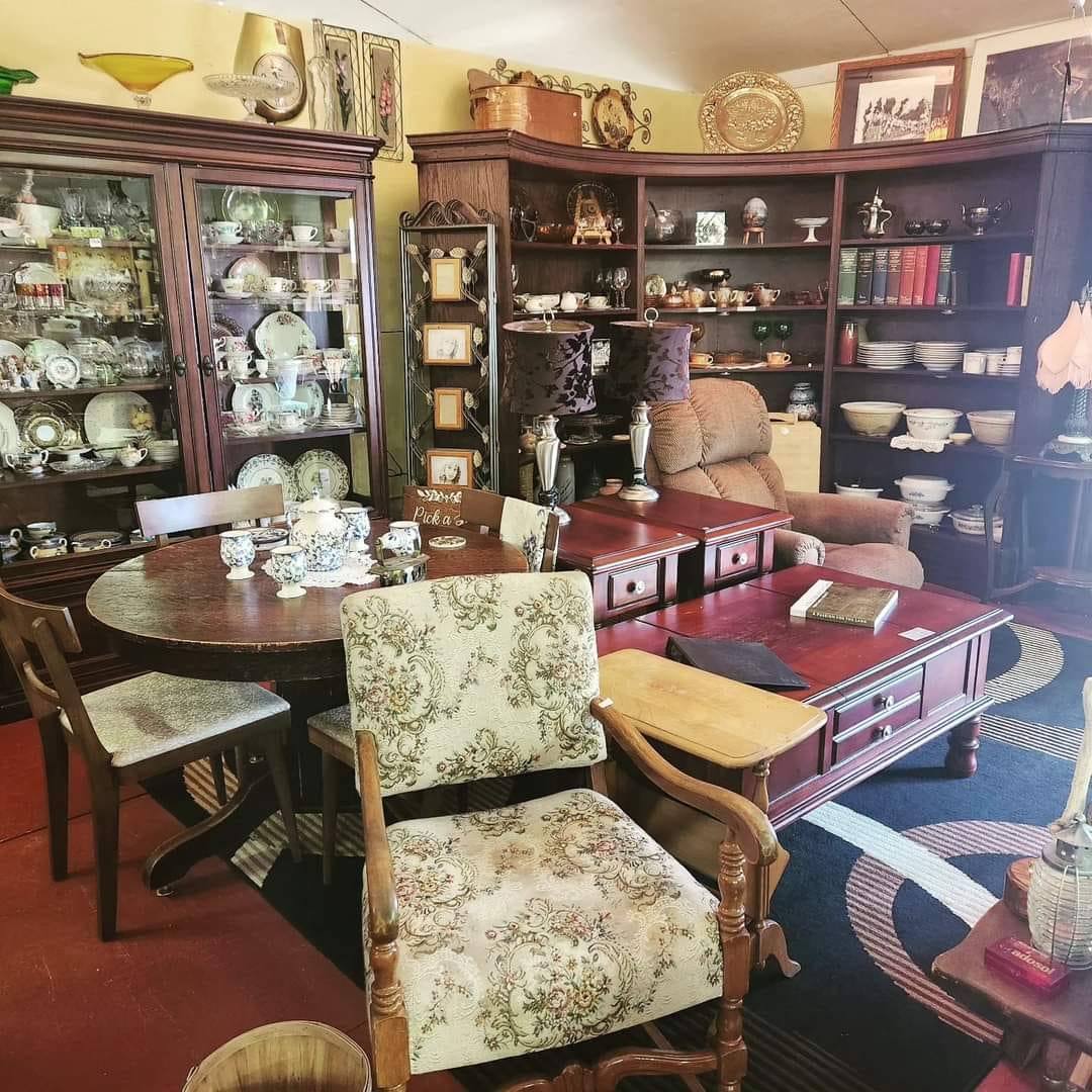 Room full of antique furniture, dishes, lamps and art.